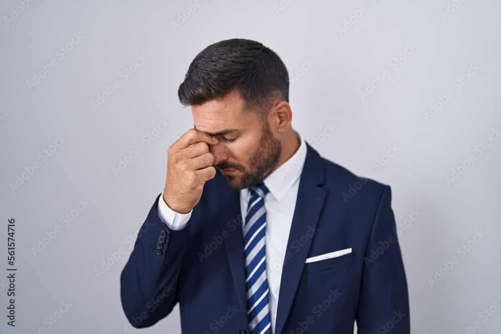 Handsome hispanic man wearing suit and tie tired rubbing nose and eyes feeling fatigue and headache. stress and frustration concept. Handsome hispanic man wearing suit and tie tired rubbing nose and eyes feeling fatigue and headache. stress and frustration concept.