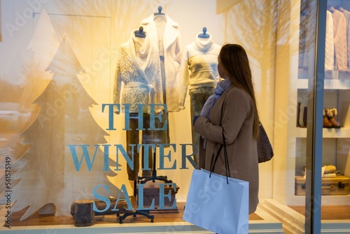 Symbolbild Winterschlussverkauf: Junge Frau steht vor einer Schaufensterscheibe auf der in großen Buchstaben THE WINTER SALE steht (Model released) photo