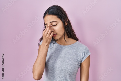 Fotobehang Young brazilian woman wearing casual t shirt over pink background tired rubbing nose and eyes feeling fatigue and headache