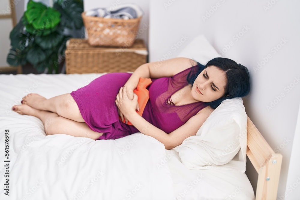 Obraz premium Young caucasian woman suffering for menstrual pain lying on bed at bedroom