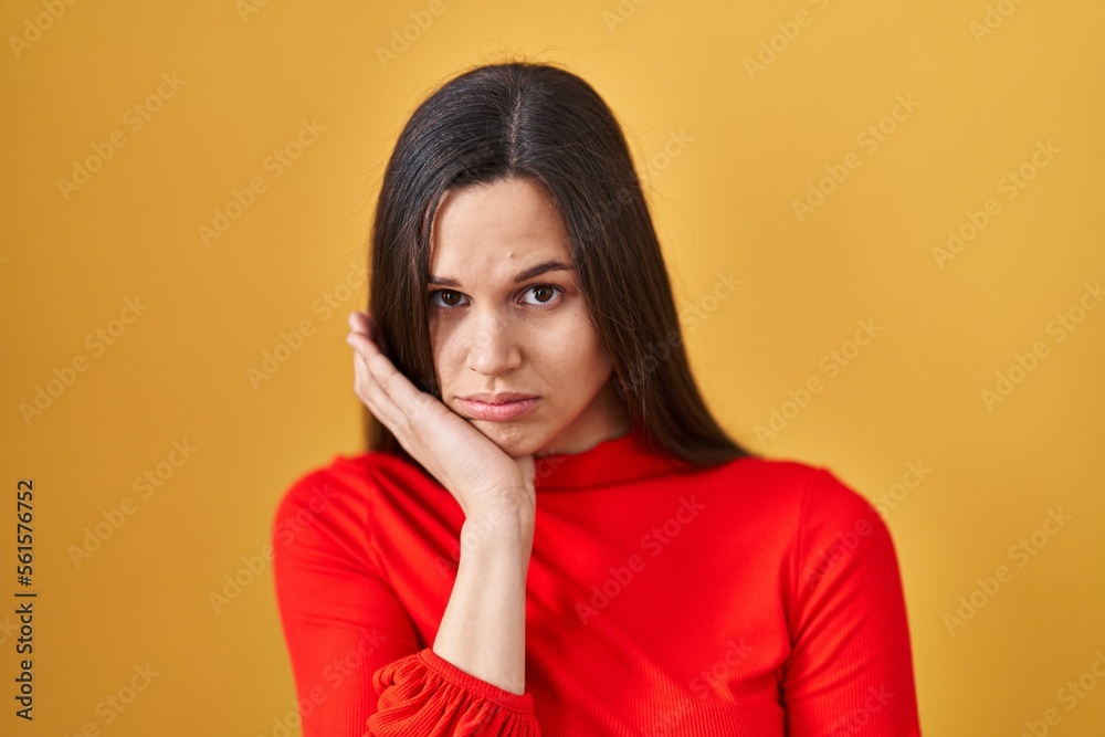 Young hispanic woman standing over yellow background thinking looking tired and bored with depression problems with crossed arms. Young hispanic woman standing over yellow background thinking looking tired and bored with depression problems with crossed arms.