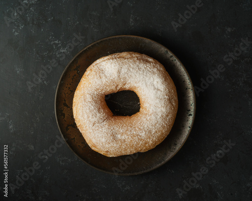 donut on a black plate and black backdrop