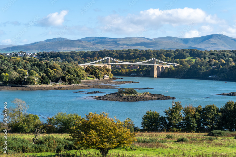 Menai Suspension Bridge over Menai Strait connecting Isle of Anglesey and mainland Wales in United Kingdom. Snowdonia mountains in the background. 