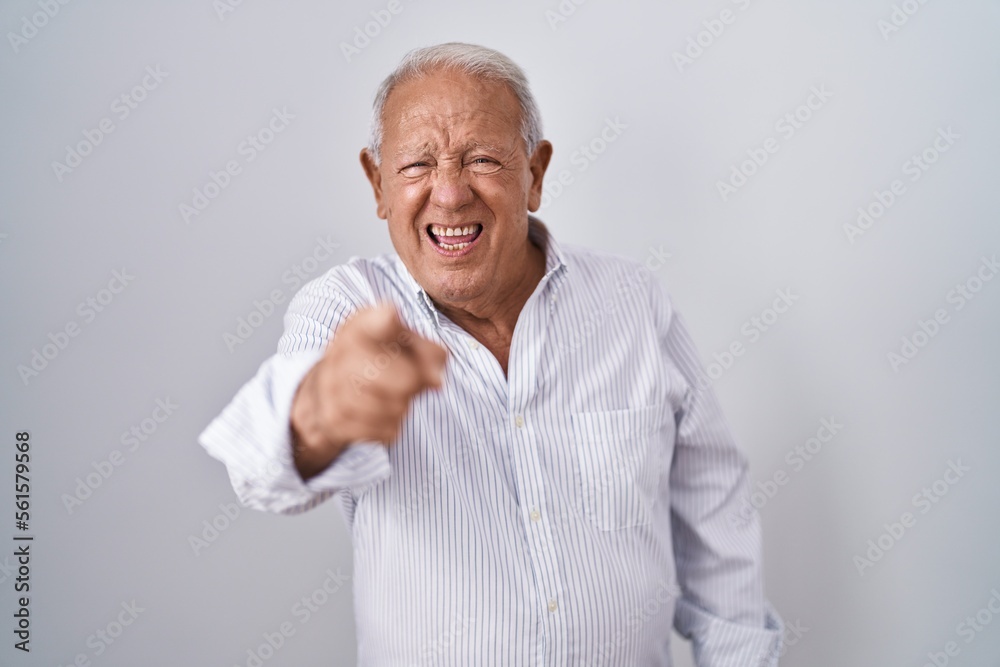 Senior man with grey hair standing over isolated background pointing displeased and frustrated to the camera, angry and furious with you Senior man with grey hair standing over isolated background pointing displeased and frustrated to the camera, angry and furious with you
