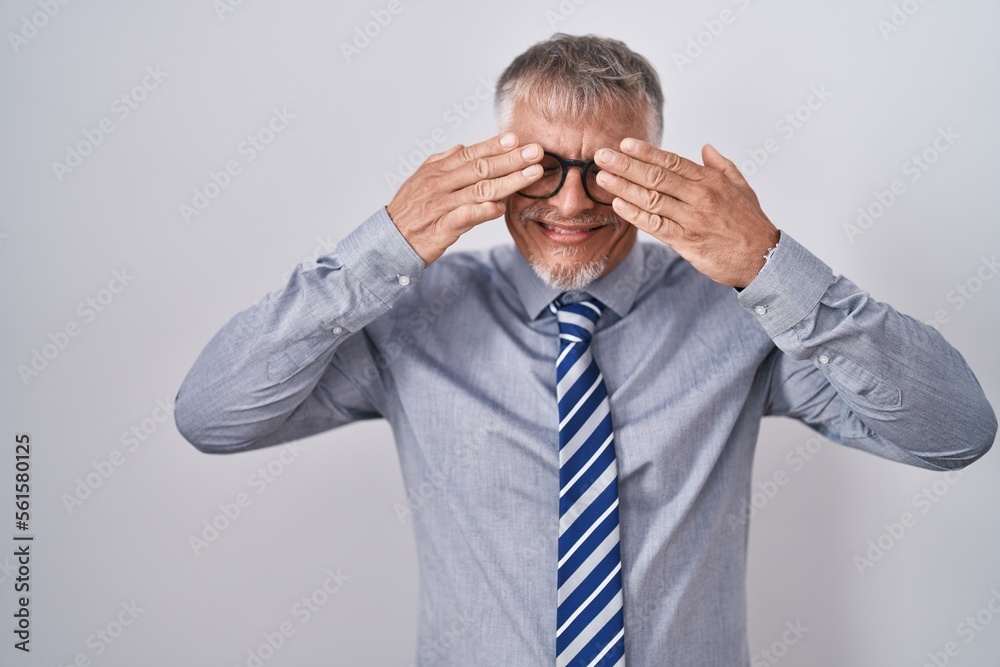 Hispanic business man with grey hair wearing glasses covering eyes with hands smiling cheerful and funny. blind concept. Hispanic business man with grey hair wearing glasses covering eyes with hands smiling cheerful and funny. blind concept.