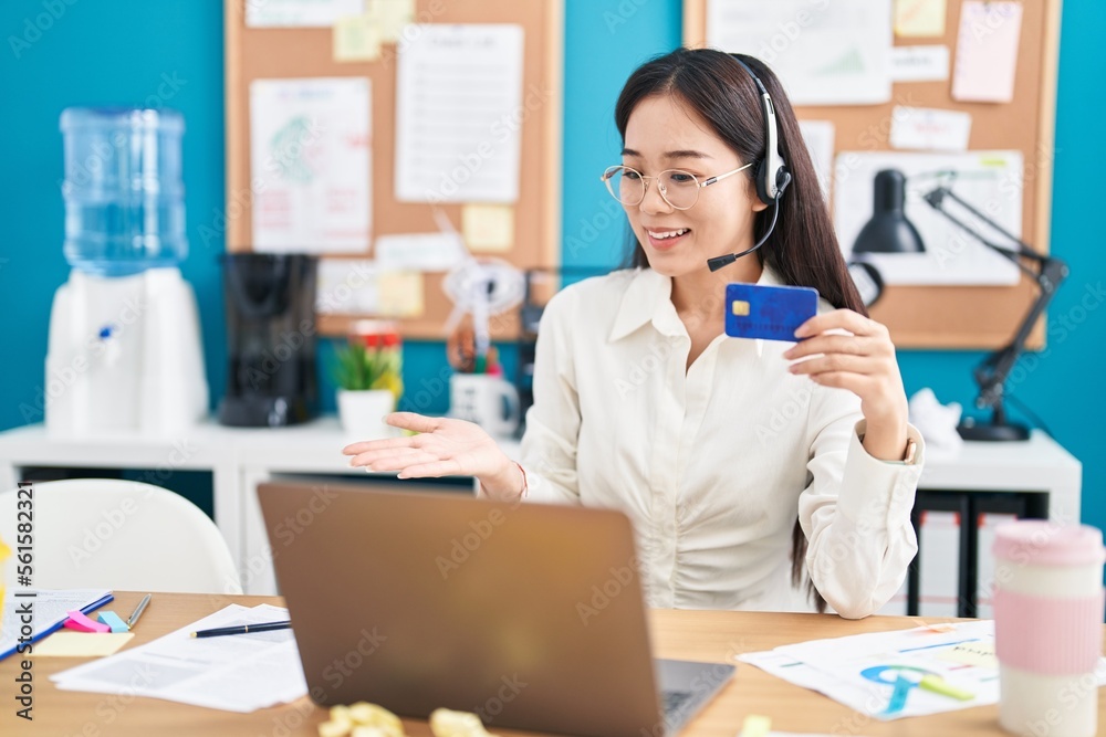 Young chinese woman working at the office doing online shopping celebrating achievement with happy smile and winner expression with raised hand Young chinese woman working at the office doing online shopping celebrating achievement with happy smile and winner expression with raised hand