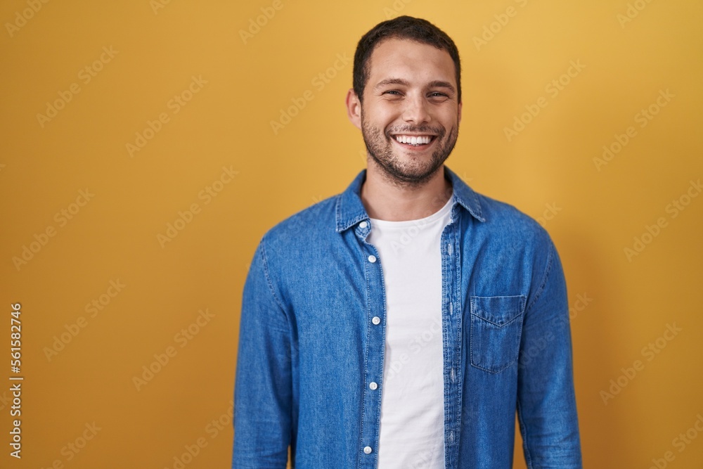 Hispanic man standing over yellow background with a happy and cool smile on face. lucky person. Hispanic man standing over yellow background with a happy and cool smile on face. lucky person.