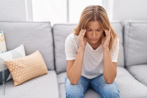 Young blonde girl stressed sitting on sofa at home