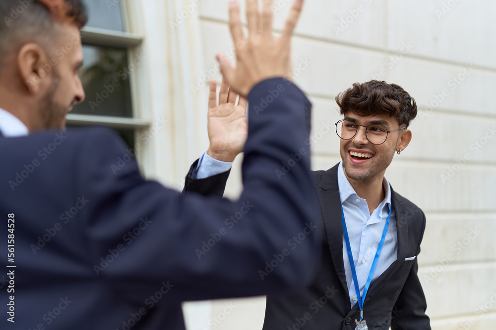 Two hispanic men business workers high five with hands raised up at street Two hispanic men business workers high five with hands raised up at street