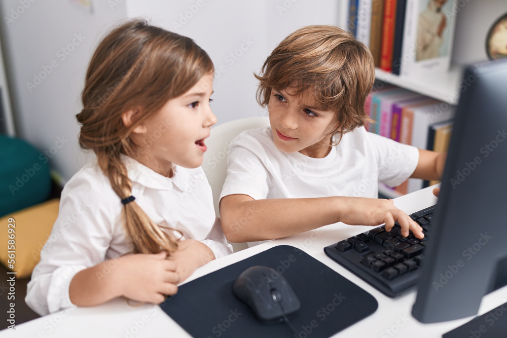 Brother and sister students using computer sitting on table at classroom Brother and sister students using computer sitting on table at classroom