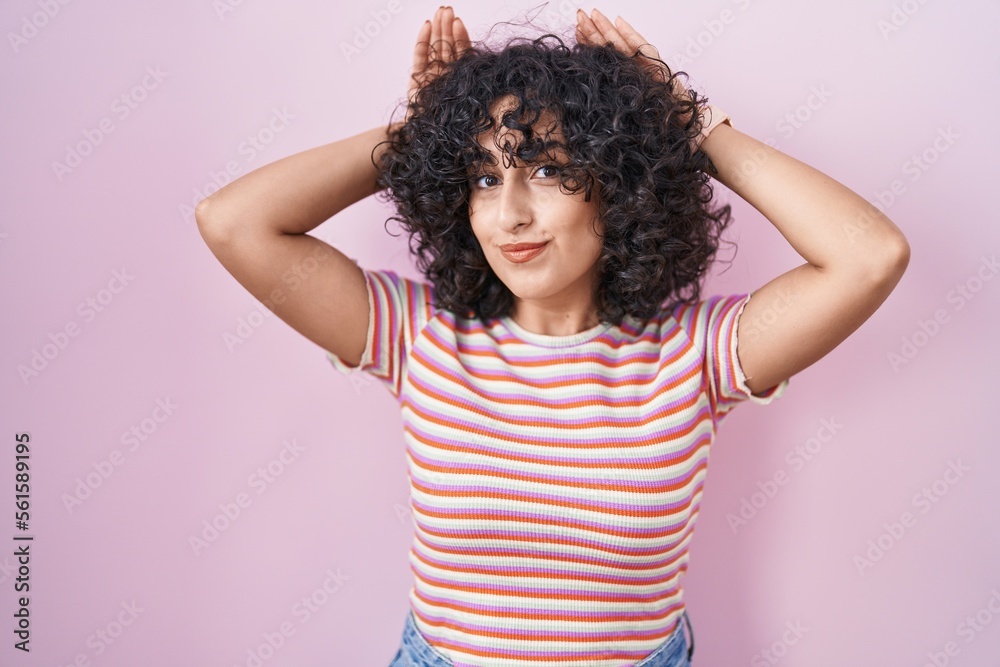 Young middle east woman standing over pink background doing bunny ears gesture with hands palms looking cynical and skeptical. easter rabbit concept. Young middle east woman standing over pink background doing bunny ears gesture with hands palms looking cynical and skeptical. easter rabbit concept.