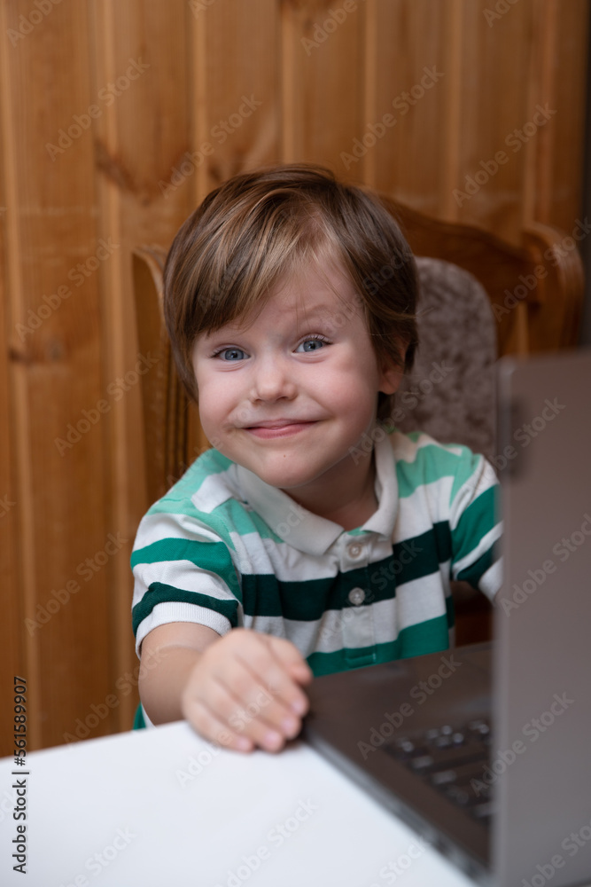 The boy sits at the laptop, the child learns remotely at the computer, classes online The boy sits at the laptop, the child learns remotely at the computer, classes online