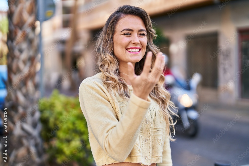 Young woman smiling confident doing coming gesture with finger at street Young woman smiling confident doing coming gesture with finger at street