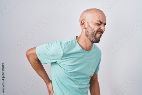 Middle age bald man standing over white background suffering of backache, touching back with hand, muscular pain © Krakenimages.com