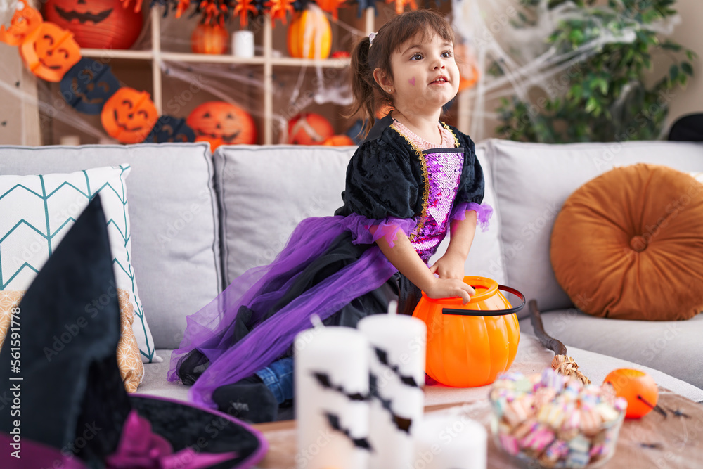 Adorable hispanic girl wearing halloween costume holding sweets at home