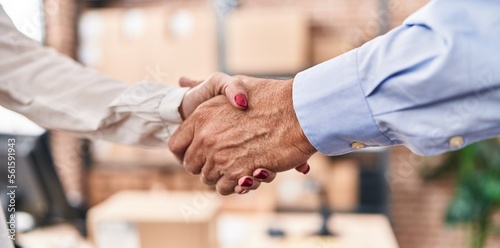 Middle age man and woman ecommerce business workers shake hands at office