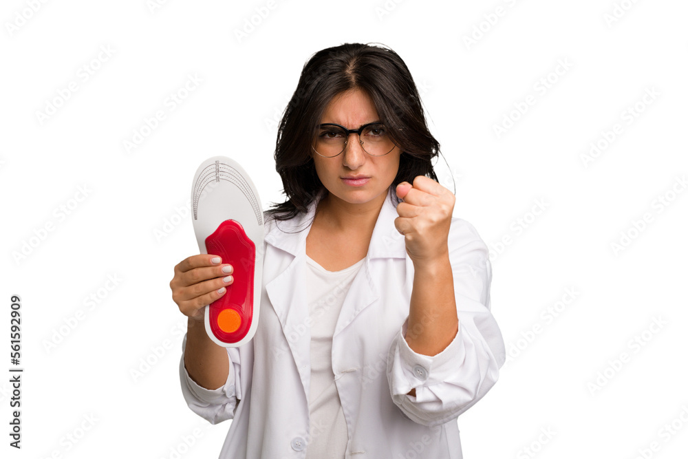 Young indian chiropodist woman holding a insoles for shoes cut out isolated showing fist to camera, aggressive facial expression. Young indian chiropodist woman holding a insoles for shoes cut out isolated showing fist to camera, aggressive facial expression.