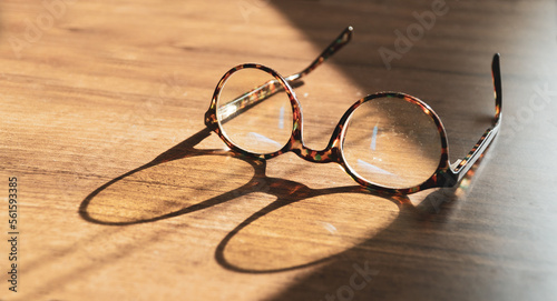 Glasses on wooden table. Sunshine reflecting on vintage glasses on the table. Wisdom concept. Copy space for text.