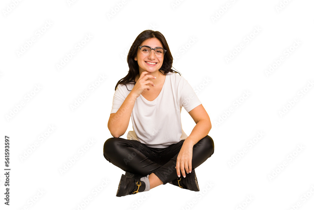 Young indian woman sitting on the floor cut out isolated smiling happy and confident, touching chin with hand. Young indian woman sitting on the floor cut out isolated smiling happy and confident, touching chin with hand.