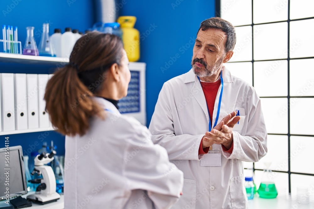 Middle age man and woman scientists having conversation at laboratory