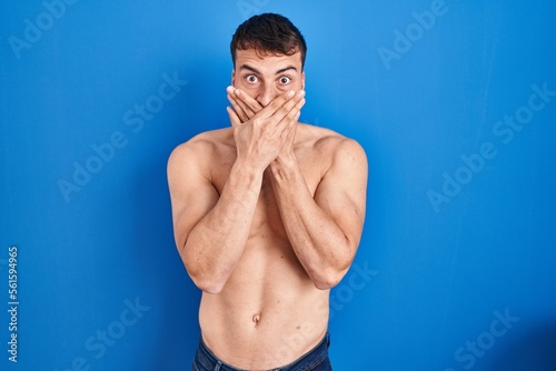 Handsome hispanic man standing shirtless shocked covering mouth with hands for mistake. secret concept.