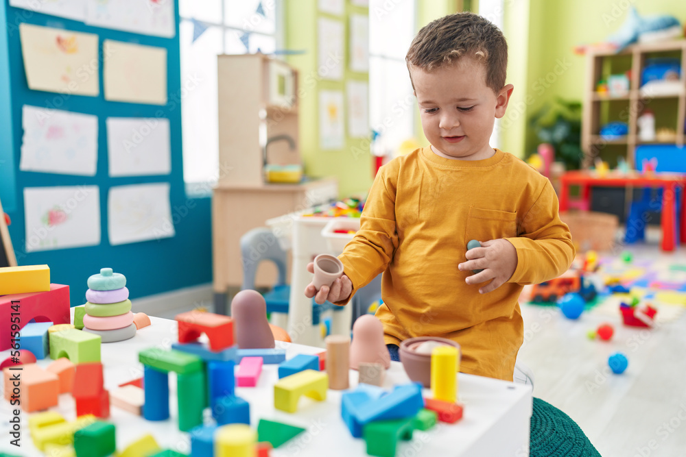 Adorable caucasian boy playing with toys sitting on floor at kindergarten Adorable caucasian boy playing with toys sitting on floor at kindergarten
