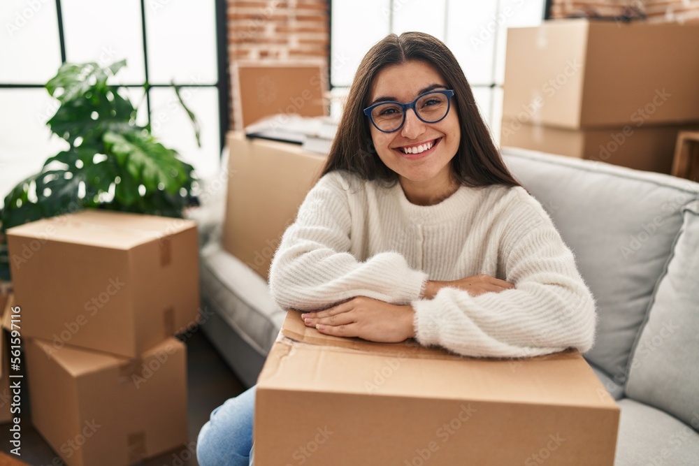 Young hispanic woman smiling confident leaning on package at new home Young hispanic woman smiling confident leaning on package at new home