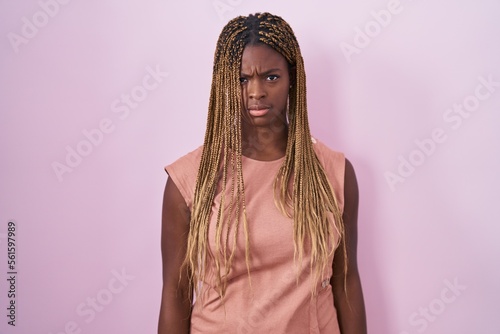 African american woman with braided hair standing over pink background skeptic and nervous, frowning upset because of problem. negative person. photo