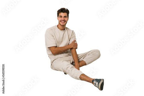 Young caucasian man sitting on the floor isolated on white background