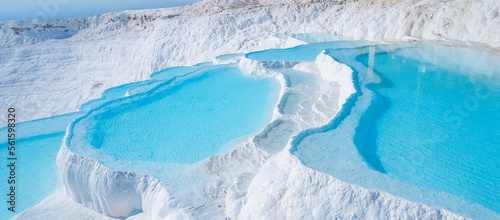 Thermal springs, natural baths Pamukkale, banner landmark of Turkey. Aerial top view blue water in travertine pool