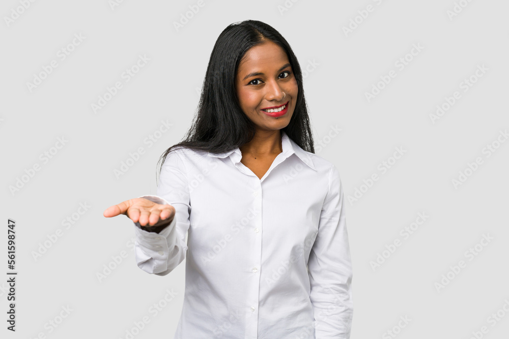 Young Indian woman cut out isolated on white background stretching hand at camera in greeting gesture. Young Indian woman cut out isolated on white background stretching hand at camera in greeting gesture.