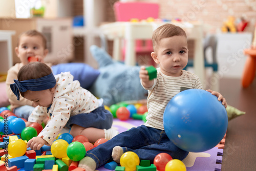 Group of toddlers playing with toys sitting on floor at kindergarten