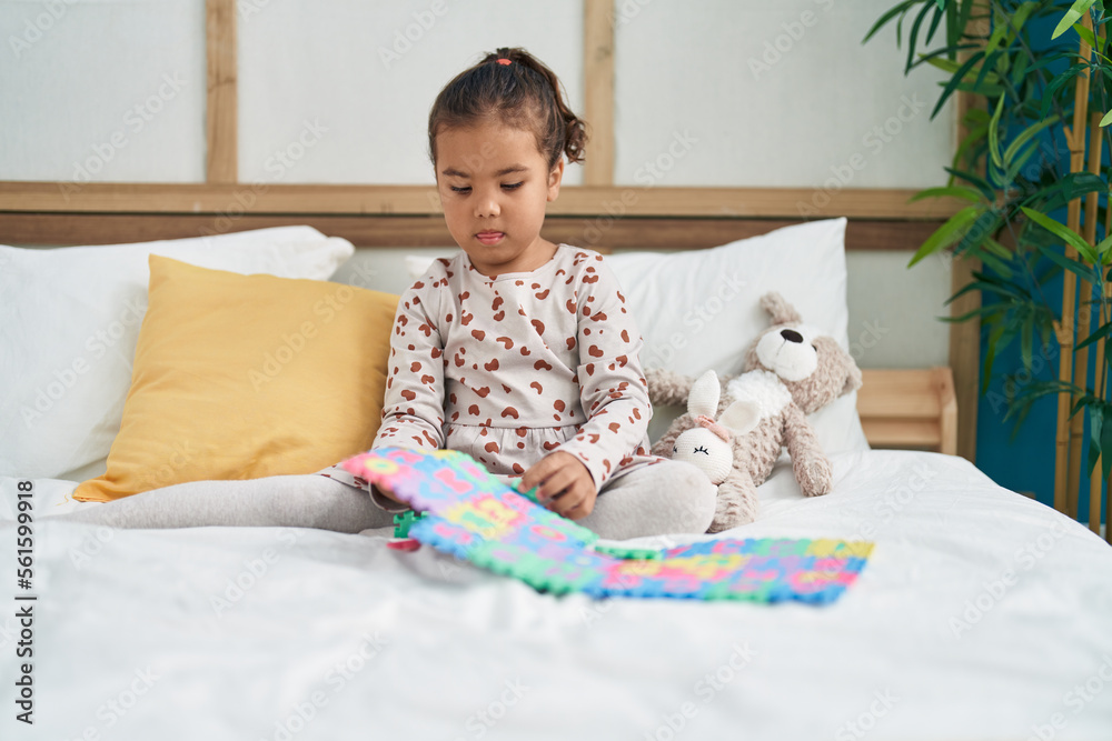 Fototapeta premium Adorable hispanic girl playing maths game sitting on bed at bedroom