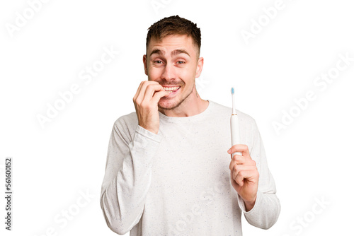 Young caucasian man holding an electric toothbrush isolated cut out biting fingernails, nervous and very anxious.