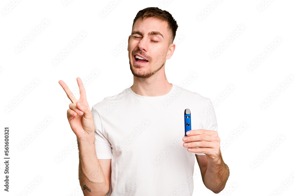 Young caucasian man holding a vaporizer cut out isolated joyful and carefree showing a peace symbol with fingers. Young caucasian man holding a vaporizer cut out isolated joyful and carefree showing a peace symbol with fingers.