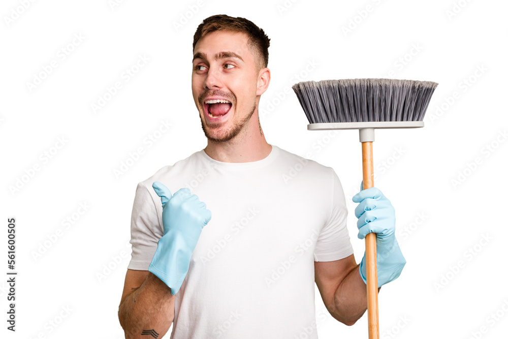 Φωτογραφία Young man holding a broom to clean his house cut out isolated points with thumb finger away, laughing and carefree