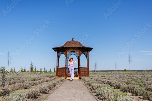 Happy young woman running in a lavender field. Dressed in purple clothes and a hat. A walk in the fresh air on a sunny summer day © Дмитрий Ткачук