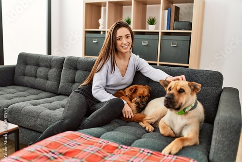 Young hispanic woman smiling confident sitting on sofa with dogs at home © Krakenimages.com