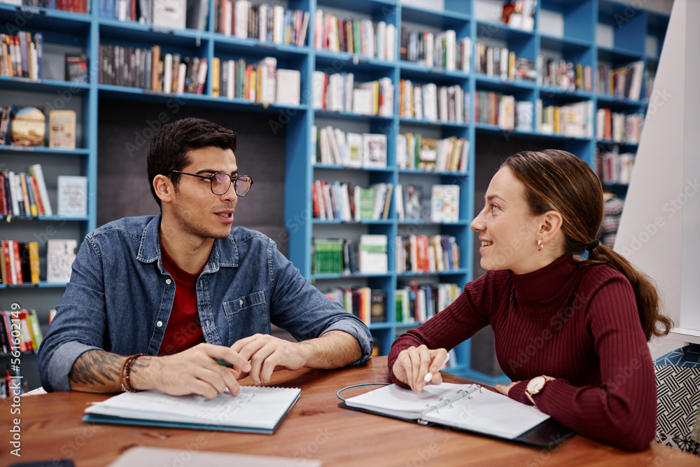 Two smiling young people, boy and girl studying together in college library Two smiling young people, boy and girl studying together in college library