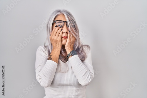 Middle age woman with grey hair standing over white background rubbing eyes for fatigue and headache, sleepy and tired expression. vision problem