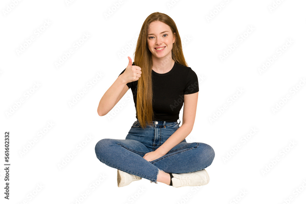 Young redhead woman sitting on the floor cut out isolated smiling and raising thumb up Young redhead woman sitting on the floor cut out isolated smiling and raising thumb up
