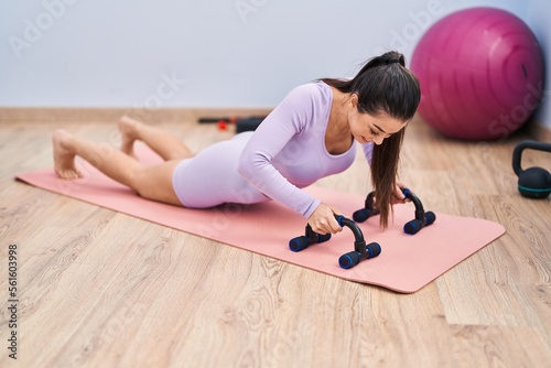 Young beautiful hispanic woman smiling confident training push up at sport center