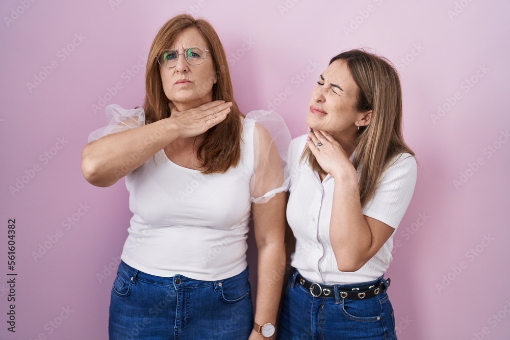 Hispanic mother and daughter wearing casual white t shirt over pink background cutting throat with hand as knife, threaten aggression with furious violence Hispanic mother and daughter wearing casual white t shirt over pink background cutting throat with hand as knife, threaten aggression with furious violence