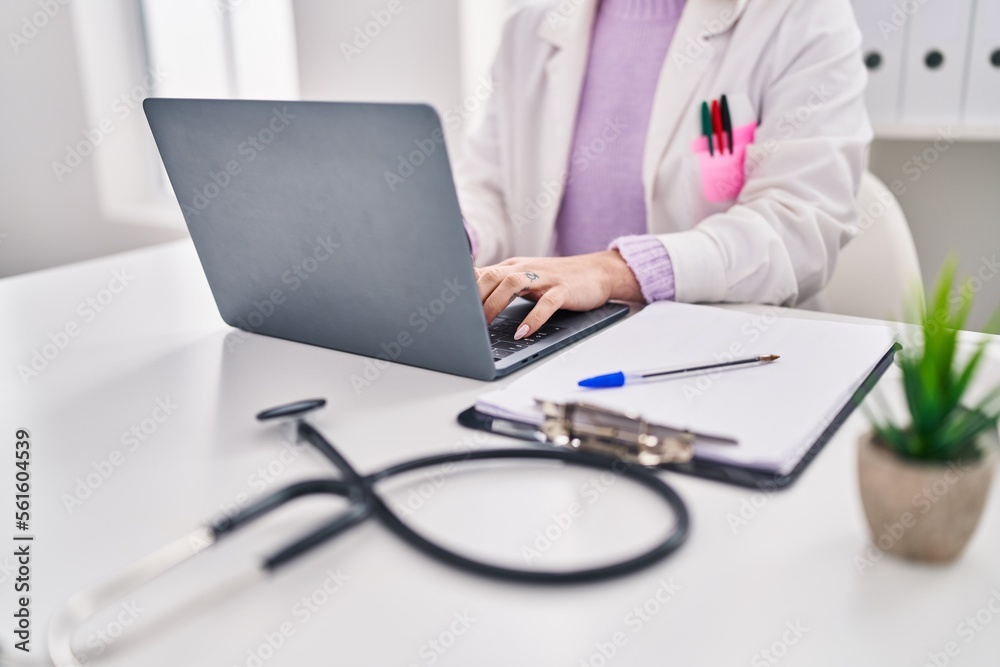 Young caucasian woman doctor using laptop sitting on table at clinic Young caucasian woman doctor using laptop sitting on table at clinic