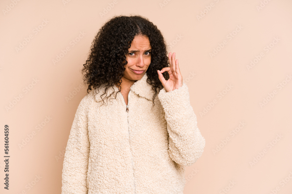 Young african american curly woman isolated winks an eye and holds an okay gesture with hand. Young african american curly woman isolated winks an eye and holds an okay gesture with hand.