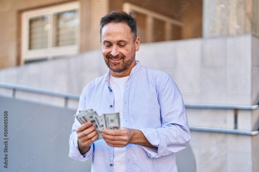 Young caucasian man smiling confident counting dollars at street Young caucasian man smiling confident counting dollars at street