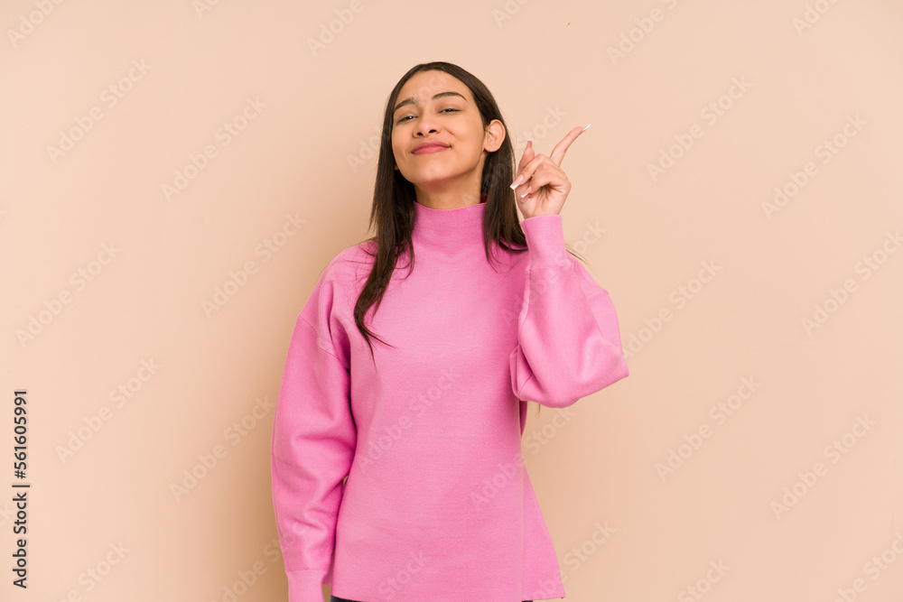 Young colombian woman isolated on beige background showing number one with finger. Young colombian woman isolated on beige background showing number one with finger.