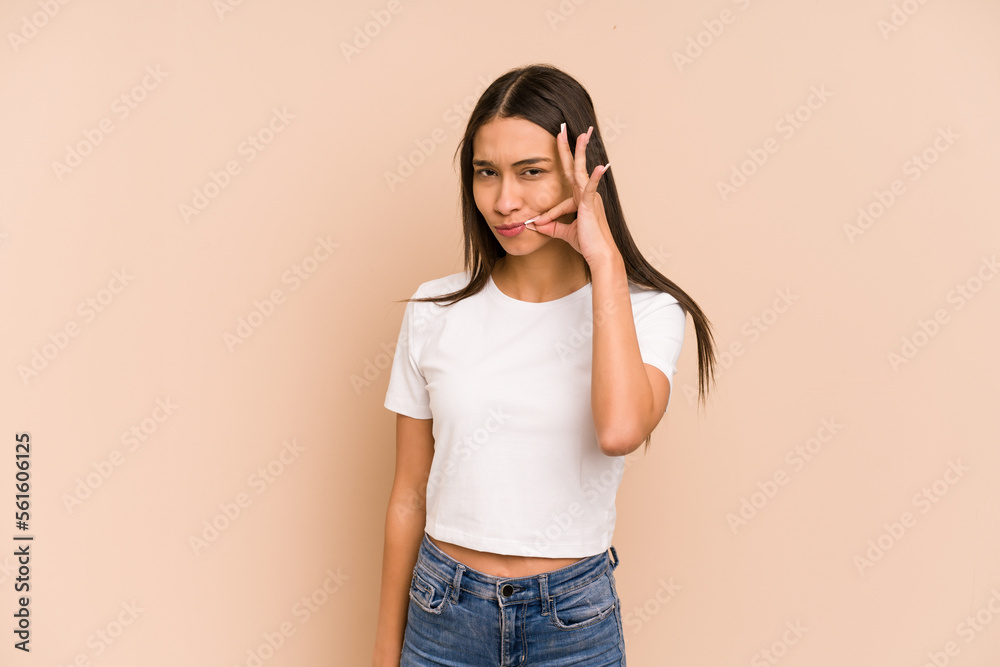Young colombian woman isolated on beige background with fingers on lips keeping a secret. Young colombian woman isolated on beige background with fingers on lips keeping a secret.