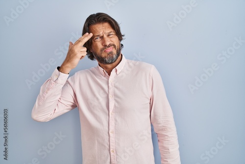 Handsome middle age man wearing elegant shirt background shooting and killing oneself pointing hand and fingers to head like gun, suicide gesture. © Krakenimages.com