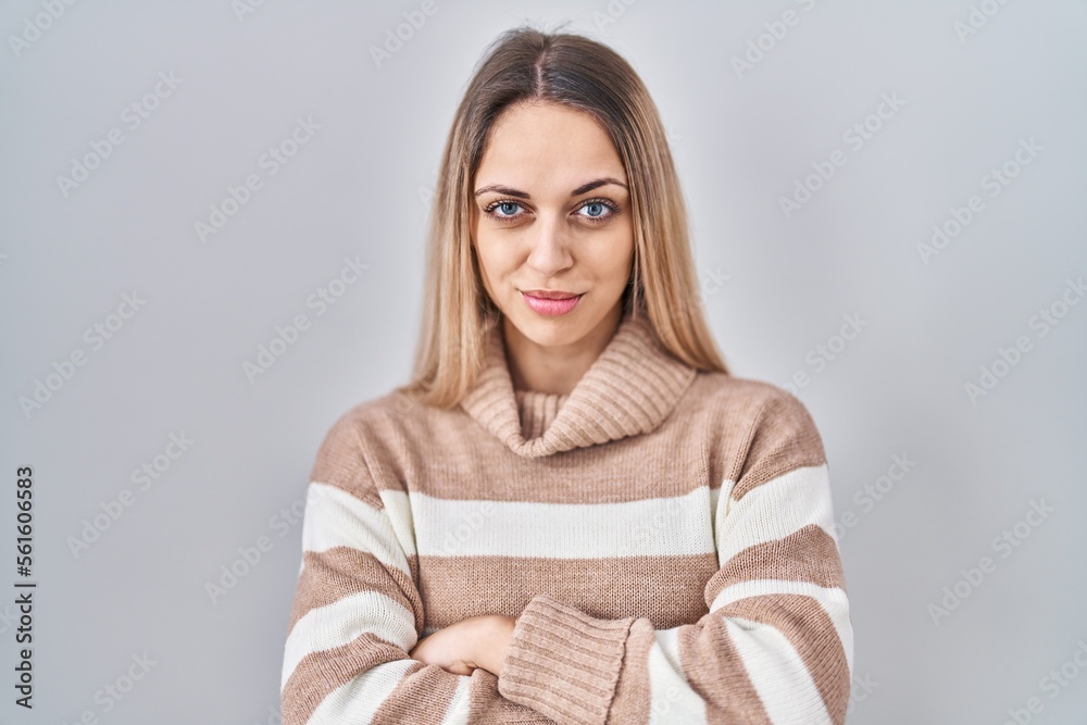 Young blonde woman wearing turtleneck sweater over isolated background skeptic and nervous, disapproving expression on face with crossed arms. negative person. Young blonde woman wearing turtleneck sweater over isolated background skeptic and nervous, disapproving expression on face with crossed arms. negative person.